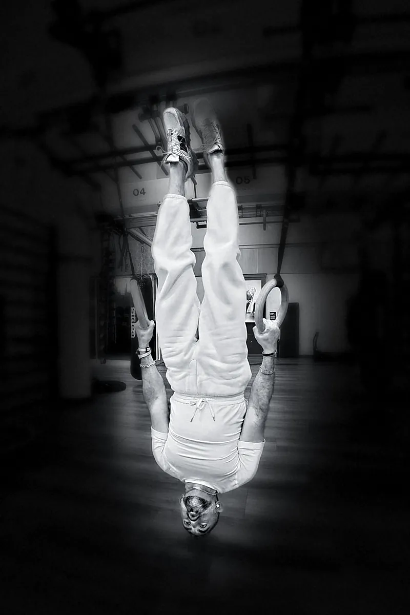 Houman Farzian in an inverted hang on the rings, black and white